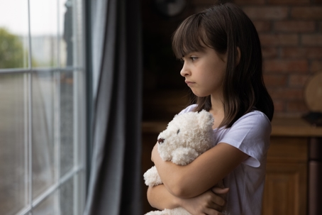 sad child hugging teddy bear