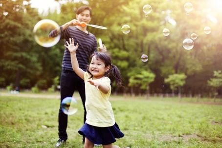 father and daughter playing outside with bubbles